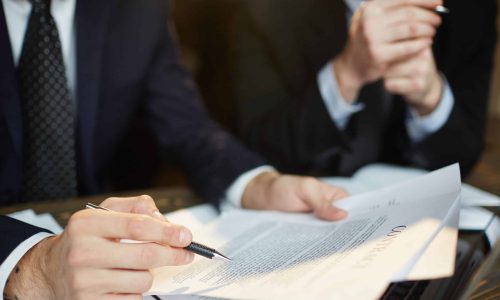 Closeup shot of unrecognizable businessman reading contract documentation at meeting with financial partner